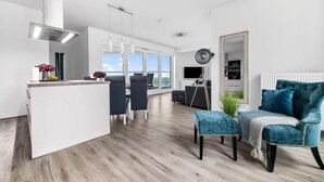 A modern living room with a large window, a kitchen area, and a dining space. - 2 bedroom cozy apartment in Olpenitz (Olpenitz)
