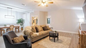A spacious living room with a sofa, armchair, coffee table, and a ceiling fan. - Charming 3-bedroom house in Navarre -5 Mins from Beach. (Navarre)