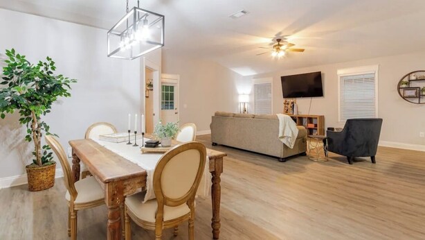 A spacious living area with a wooden dining table, chairs, a sofa, and a TV mounted on the wall. - Charming 3-bedroom house in Navarre -5 Mins from Beach. (Navarre)