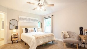 A bedroom with a bed, a chair, a nightstand, a ceiling fan, and a window. - Charming 3-bedroom house in Navarre -5 Mins from Beach. (Navarre)