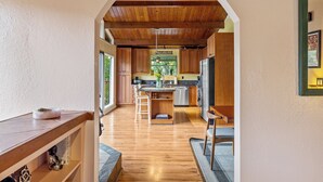 Una cocina con armarios de madera, una isla central y vistas a un comedor a través de un arco.