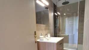 Un baño moderno con tocador, espejo y ducha.