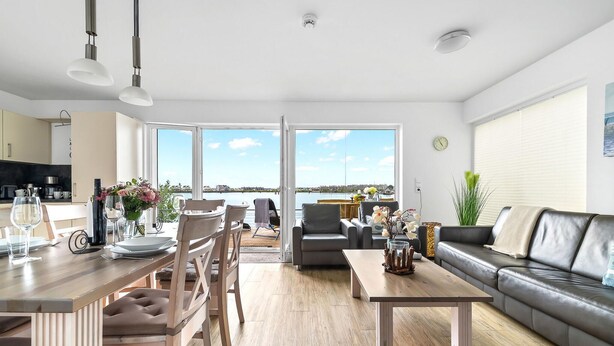 Un salon moderne comprenant un coin repas, un canapé et une vue sur la mer.