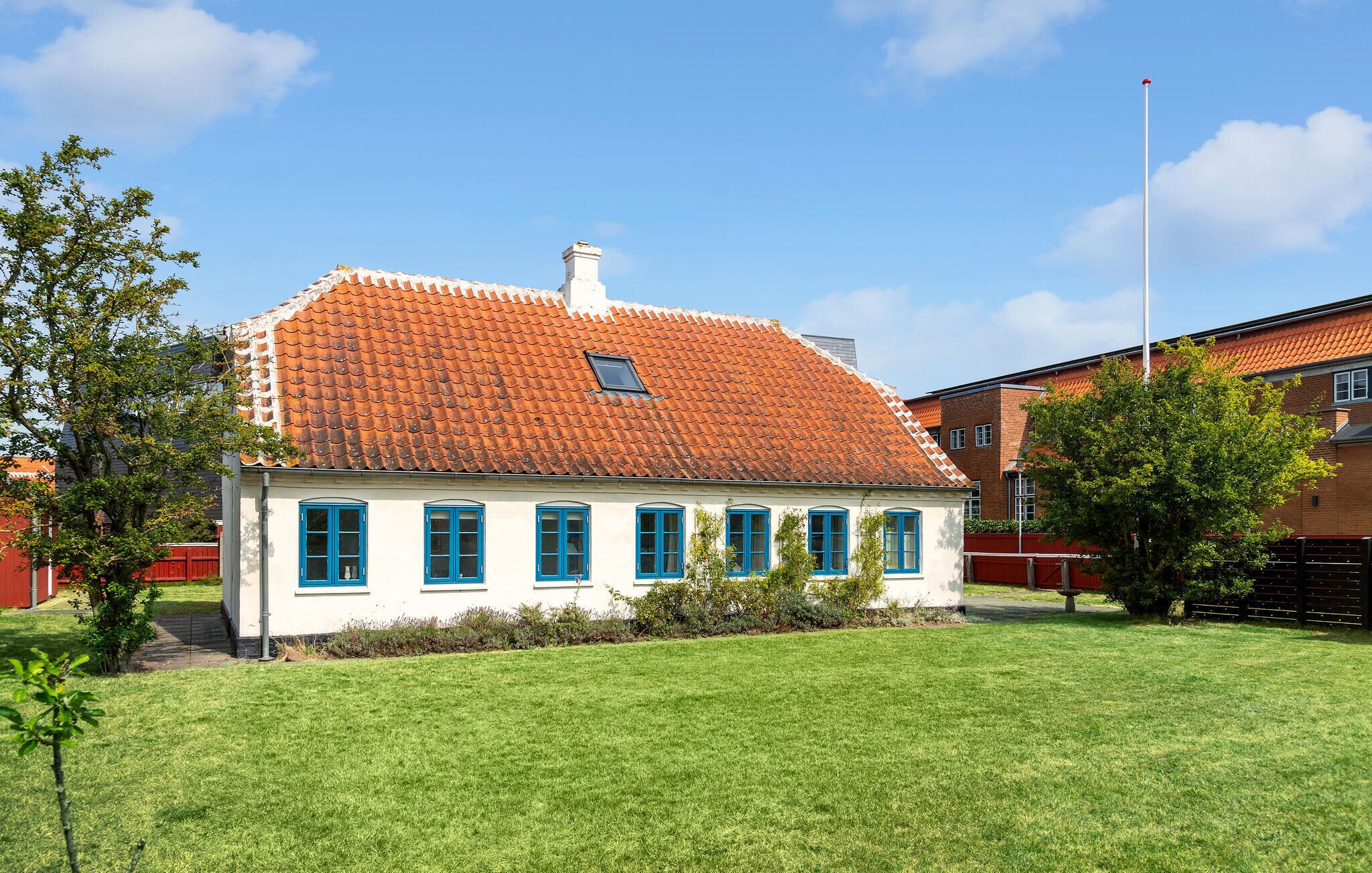 A white building with a red-tiled roof and blue windows.