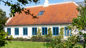 Een wit gebouw met blauwe ramen en een rode pannendak.