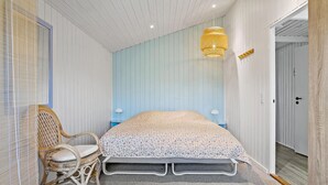 Quarto com cama, cadeira, luminária e porta.