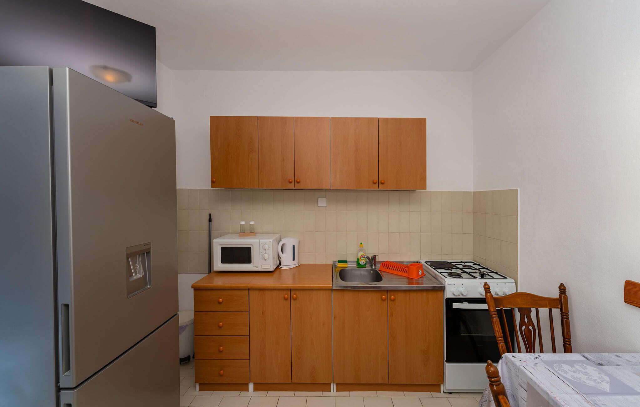 A compact kitchen with wooden cabinets, a microwave, a gas stove, and a refrigerator.