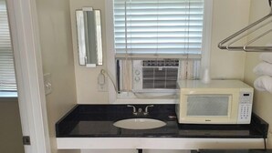 A small bathroom with a sink, mirror, and a microwave. - Sea Shell Motel (Westerly)