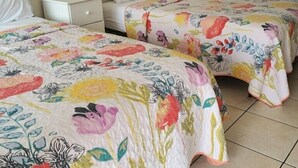 A hotel room with two beds, a nightstand, a lamp, and a wooden headboard. - Sea Shell Motel (Westerly)