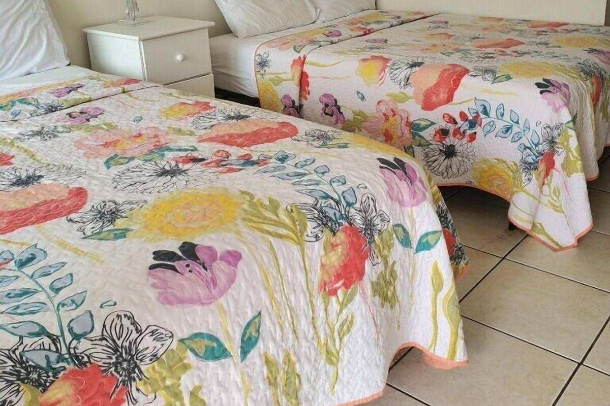 A hotel room with two beds, a nightstand, a lamp, and a wooden headboard.