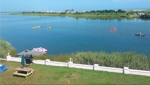 A calm lake with kayaks and canoes, a picnic area, and a distant building. - Sea Shell Motel (Westerly)