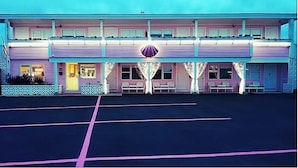 A two-story motel with a flat roof, a central entrance, and a parking lot in front. - Sea Shell Motel (Westerly)