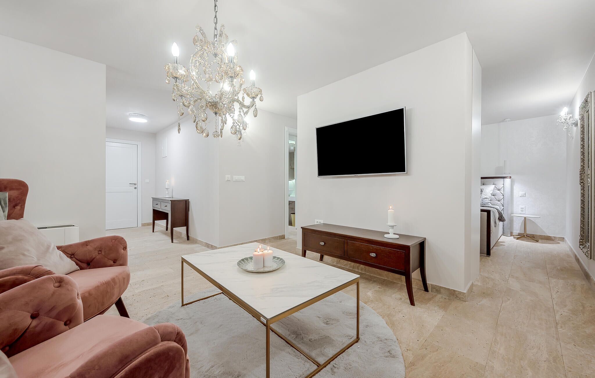 Un salon moderne doté d’un lustre, d’un téléviseur, d’une cheminée et d’un coin salon confortable.