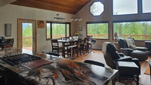 A spacious kitchen with a large island, wooden ceiling, and large windows offering a view of the outdoors. - Spacious Lodge in Charming Palmer with Incredible Mountain Views (Palmer)