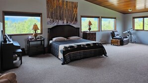 A spacious bedroom with a large bed, two bedside tables with lamps, a desk, a chair, and a telescope. - Spacious Lodge in Charming Palmer with Incredible Mountain Views (Palmer)