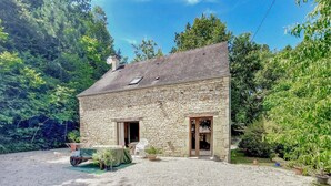 A stone house with a sloped roof, a front door, and a small porch area with outdoor seating. - Lovely home in Paulin with kitchen (Paulin)