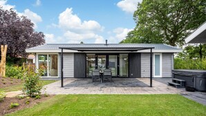 A modern house with a covered patio, a dining area, and a barbecue setup. - Luxurious home in Voorthuizen with WiFi (Voorthuizen)