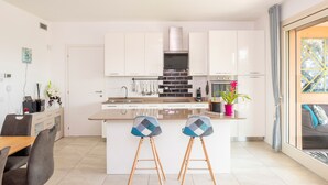 Una cocina moderna con armarios blancos, una isla central y dos taburetes.