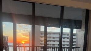 Ein Schlafzimmer mit Blick auf einen Sonnenuntergang über einer Wohngegend.