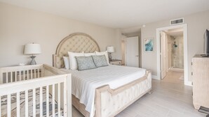 Ein Schlafzimmer mit einem großen Bett, einem Holckrippenbett, einer Kommode und einem begehbaren Kleiderschrank.