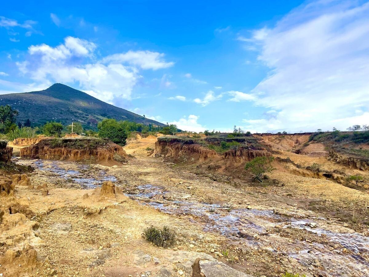 Un paisaje seco y rocoso con una cruz en una colina, lo que sugiere un sitio religioso o histórico.