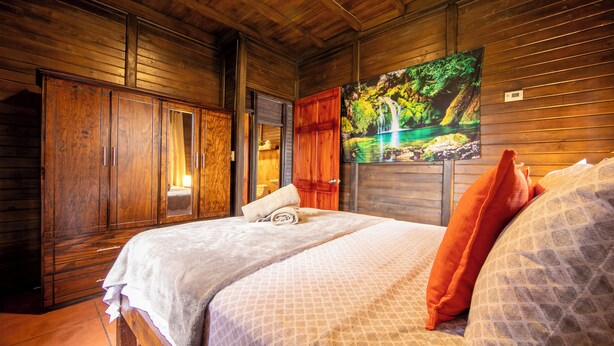 Una stanza in legno con un letto, un armadio e un quadro raffigurante una cascata.