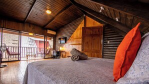 Una stanza accogliente con un letto, un soffitto in legno e un balcone con sedie e un tavolo.