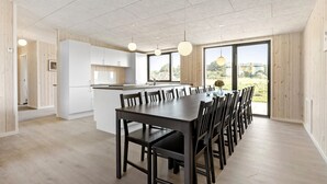 Une cuisine moderne avec des meubles blancs, un îlot central et de grandes fenêtres.