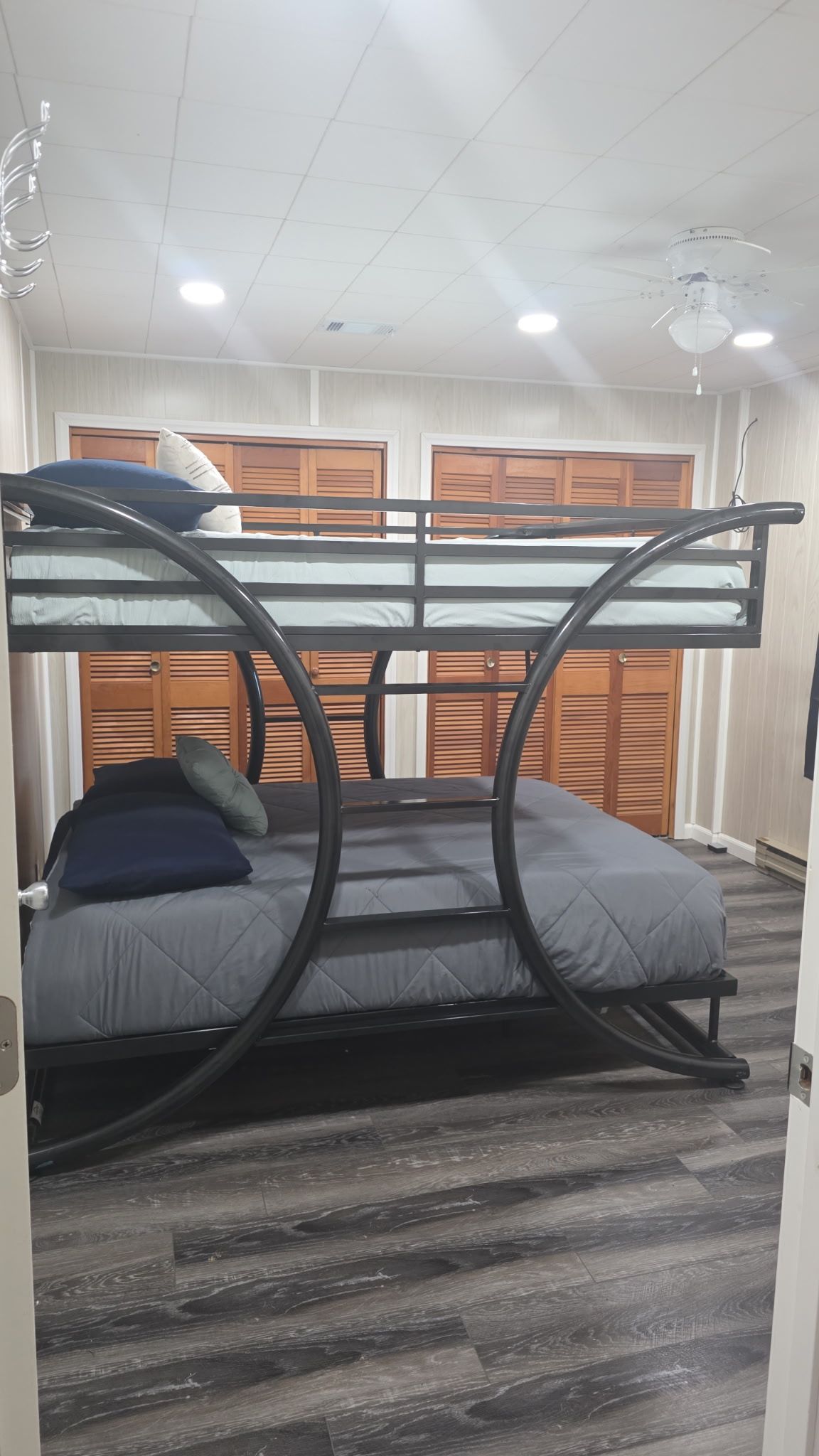Un letto a castello con struttura circolare, testiera in legno e materasso grigio.