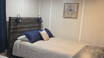 A room with a bed, a bedside table, a headboard, a wall clock, and a ceiling vent.