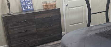 A bedroom with a bunk bed, a dresser, a lamp, and a sign on the wall.