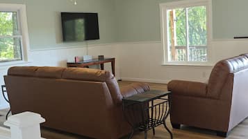 A living room with a sectional sofa, a coffee table, and a TV mounted on the wall.
