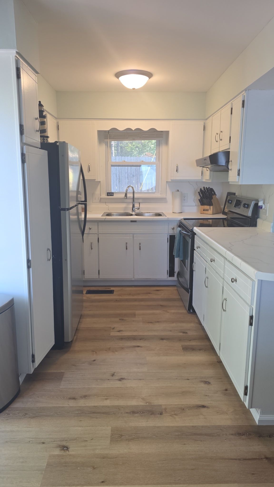 A kitchen with white cabinets, a stainless steel sink, and a built-in oven.