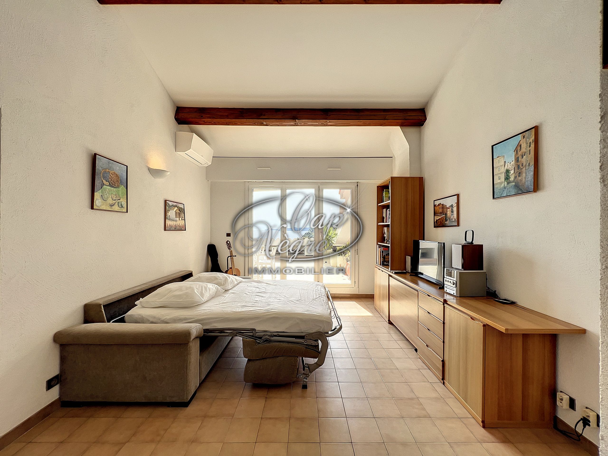 A bedroom with a bed, a bench, a TV, and a desk.