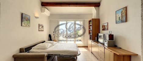 A bedroom with a bed, a bench, a TV, and a desk.