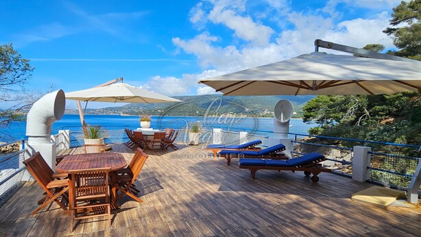 A wooden deck with outdoor furniture, a table, and umbrellas overlooking a body of water. - Waterfront house with a rooftop and private dock in Cavalière (Le Lavandou)