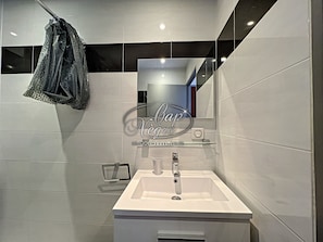 Une salle de bain moderne avec un lavabo blanc, un miroir et une serviette suspendue à un porte-serviettes.