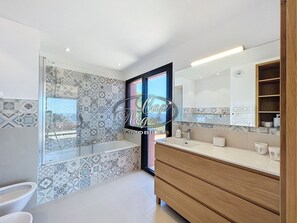 A modern bathroom with patterned tiles, a large mirror, and a wooden vanity. - Prestigious property with a pool and panoramic sea view in Cap Nègre (Le Lavandou)