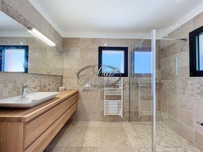 A modern bathroom with a wooden vanity, a glass shower enclosure, and a built-in towel rack. - Prestigious property with a pool and panoramic sea view in Cap Nègre (Le Lavandou)