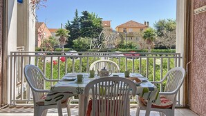 A balcony with a table set for two, white chairs, and a blue awning.