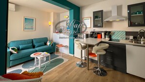 A modern kitchen with a dining area, a sofa, and a coffee table. - Modern studio with sea view and direct access to Cavalière Beach (Le Lavandou)