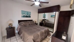 A bedroom with a bed, nightstands, a ceiling fan, a mirror, and artwork on the wall. - Charming 1-bedroom apartment w/ Purified Water, AC and WiFi in San José del Cabo (San José del Cabo B.C.S.)