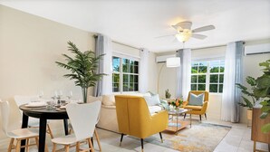 Un salon moderne avec un coin repas, comprenant un canapé, des fauteuils, une table basse et une table à manger pour quatre personnes.