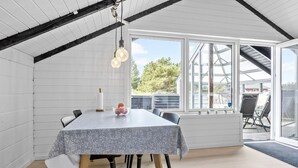 Een eethoek met een tafel, stoelen, een kaars en een raam met uitzicht.
