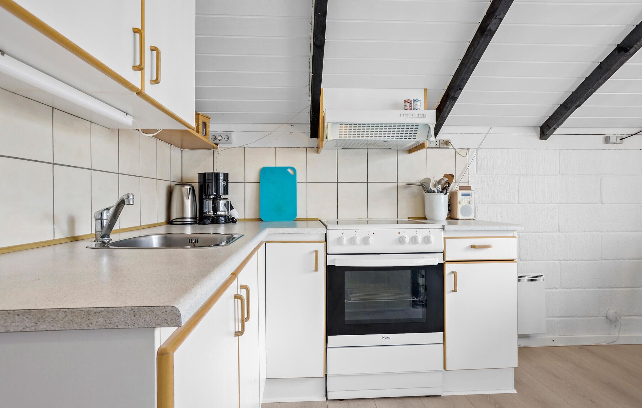 A compact kitchen with white cabinets, a stove, and a coffee maker.