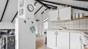Een moderne keuken met witte kasten, een ingebouwde oven en een zichtbare klok.