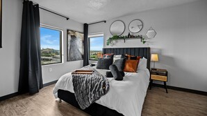 Ein modernes Schlafzimmer mit einem großen Bett, Blick auf die Stadt und einem Oberlicht.