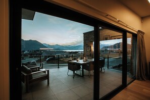 A modern balcony with a view of mountains, a dining table, and chairs. - The Heights  (Wanaka)