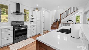 Une cuisine moderne avec des meubles blancs, une cuisinière noire et un grand îlot central doté d’un évier.