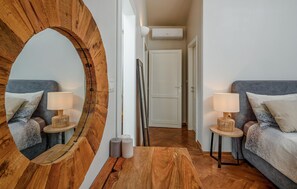 A modern bedroom with a large wooden mirror, two bedside tables with lamps, a grey sofa, and a wooden floor. - Cozy home in Klis with WiFi (Klis)